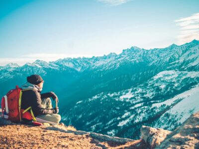 person sitting on brown soil of mountain peak